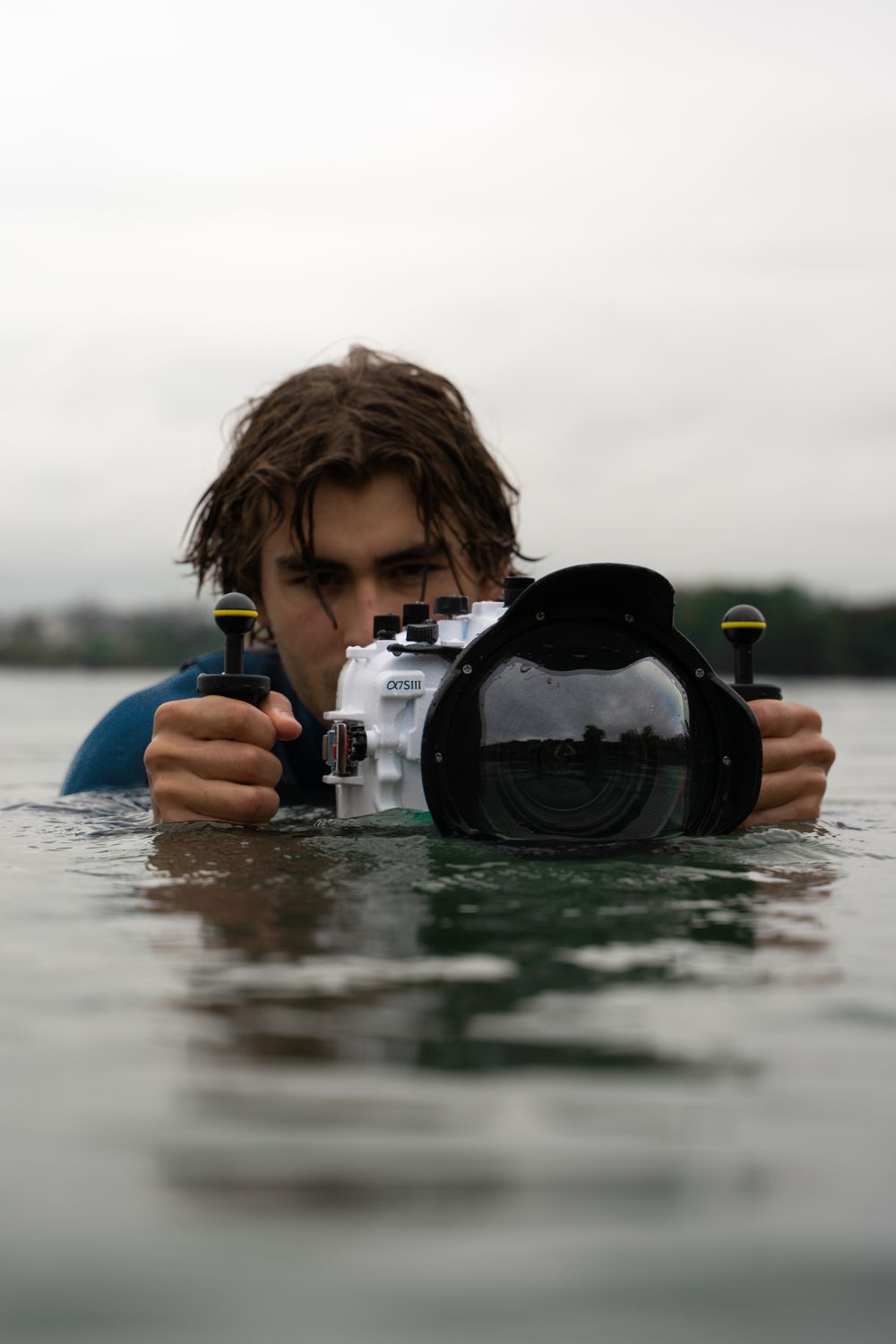 Photo de themanshot dans l'eau tenant sa caméra avec le caisson étanche